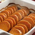 Perfect candied yams recipe with glossy caramel glaze in white baking dish for Thanksgiving dinner